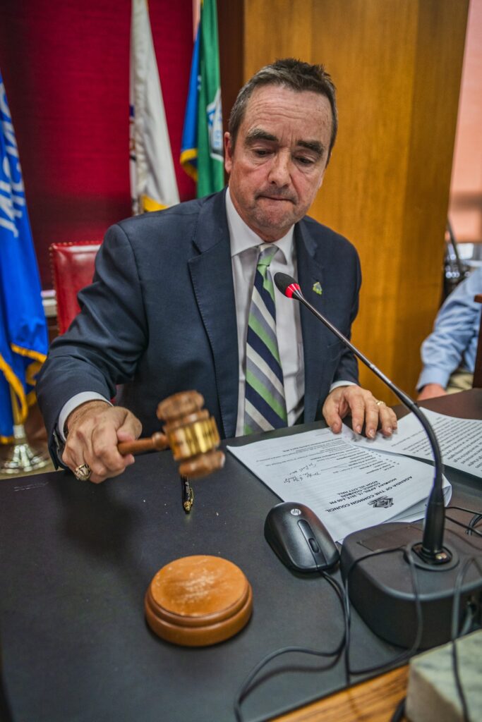 Jim Schmitt seated at the mayor's desk with a wooden gavel.