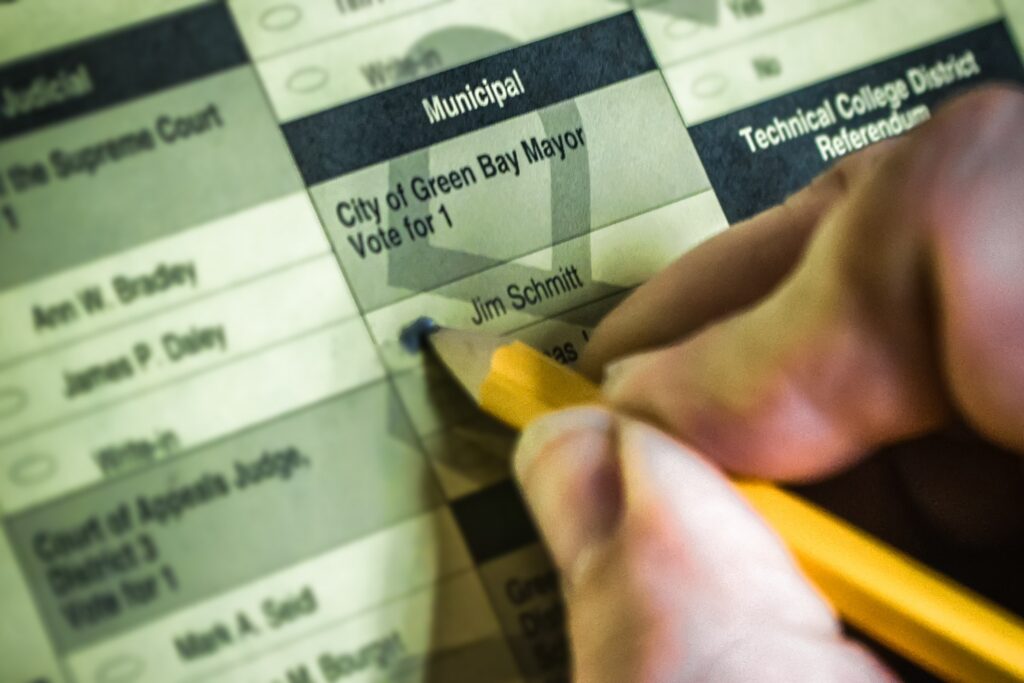 A voter marking a municipal ballot that includes City of Green Bay offices.