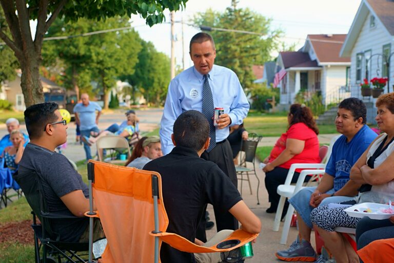 Jim Schmitt speaking with residents at an outdoor Green Bay neighborhood gathering.