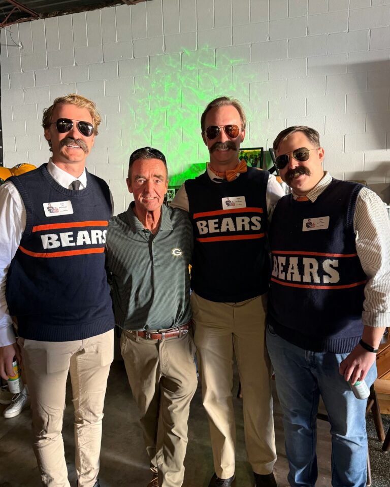 Jim Schmitt stands outdoors at a tailgate with a small group of fans, including people wearing Chicago Bears gear.